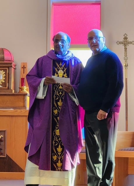 Father Joseph accepts the cheque from calendars from Grand Knight David Alm on behalf of Immaculate Heart of Mary Catholic Church in Outlook.
